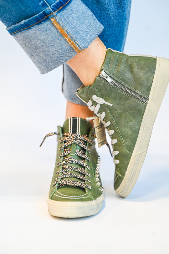 ShuShop olive green high top sneakers with white soles and leopard print laces worn with rolled-up jeans
