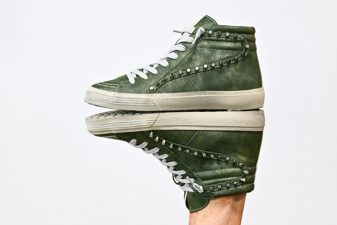 ShuShop olive green high top sneakers with white laces and studded detailing on a reflective surface
