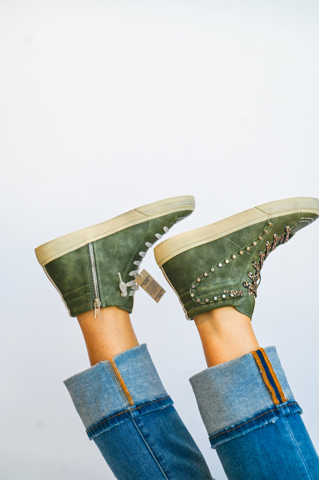 ShuShop olive green high top sneakers with side zipper and studded design worn with rolled blue jeans