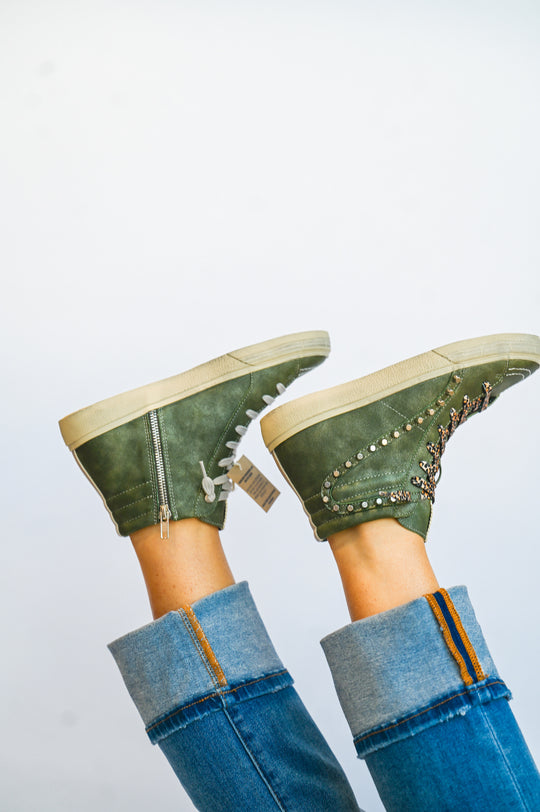 ShuShop olive green high top sneakers with side zipper and studded design worn with rolled blue jeans
