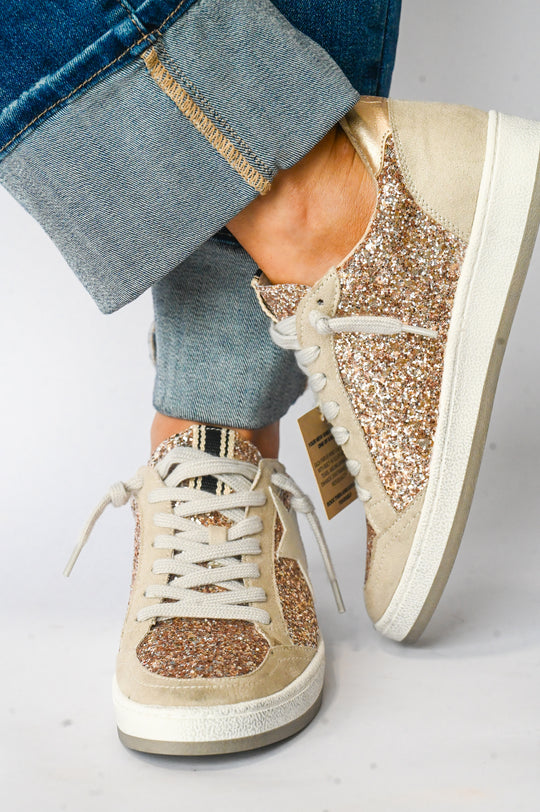 Paz Champagne Shu Shop Sneakers with glitter detail and beige suede accents worn with cuffed blue jeans