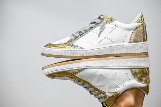 ShuShop Paz gold sneaker women with white leather and iridescent gold accents on reflective surface