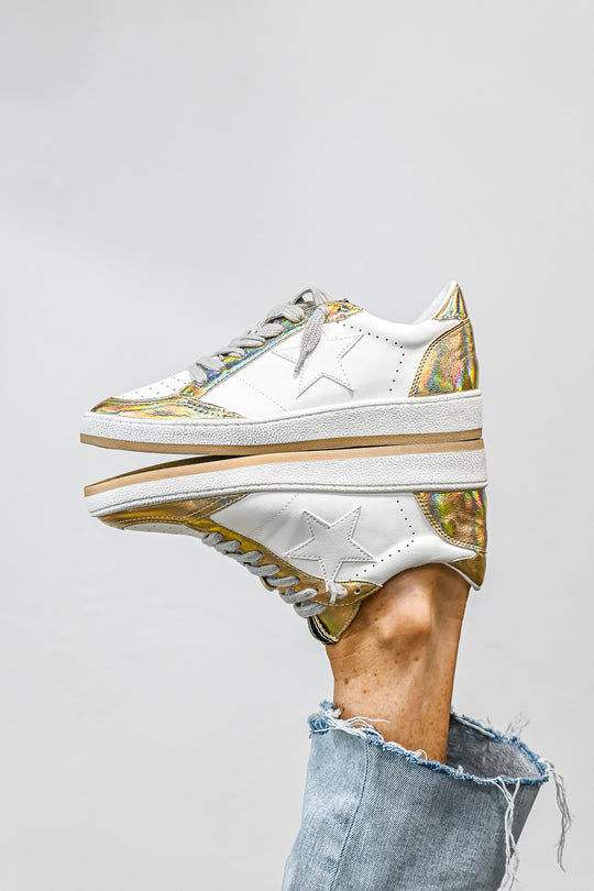 ShuShop Paz gold sneaker women with white leather and gold iridescent details on a reflective surface