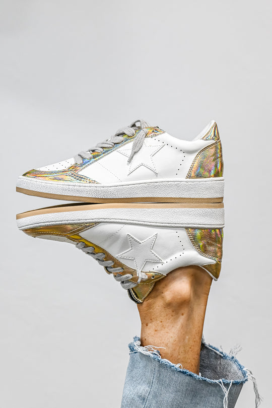 ShuShop Paz gold sneaker women with white leather and metallic gold accents on a reflective surface