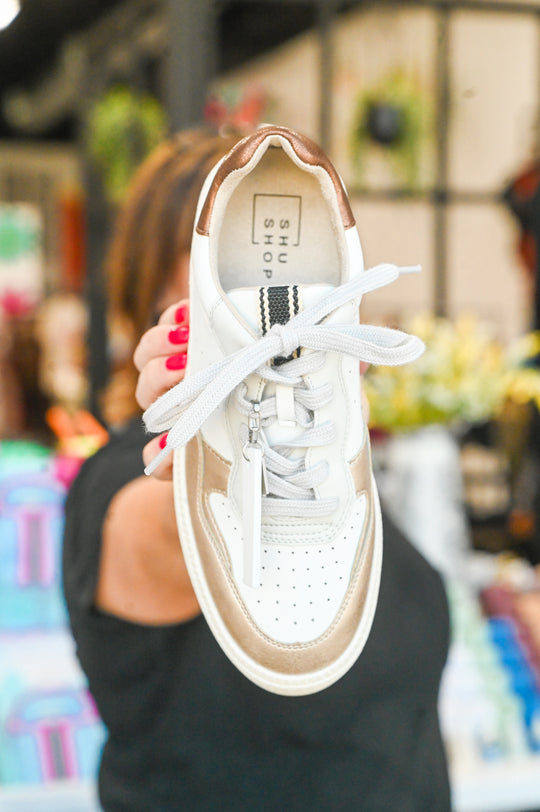 White and beige Sheena Shu Shop sneaker with white laces held in hand
