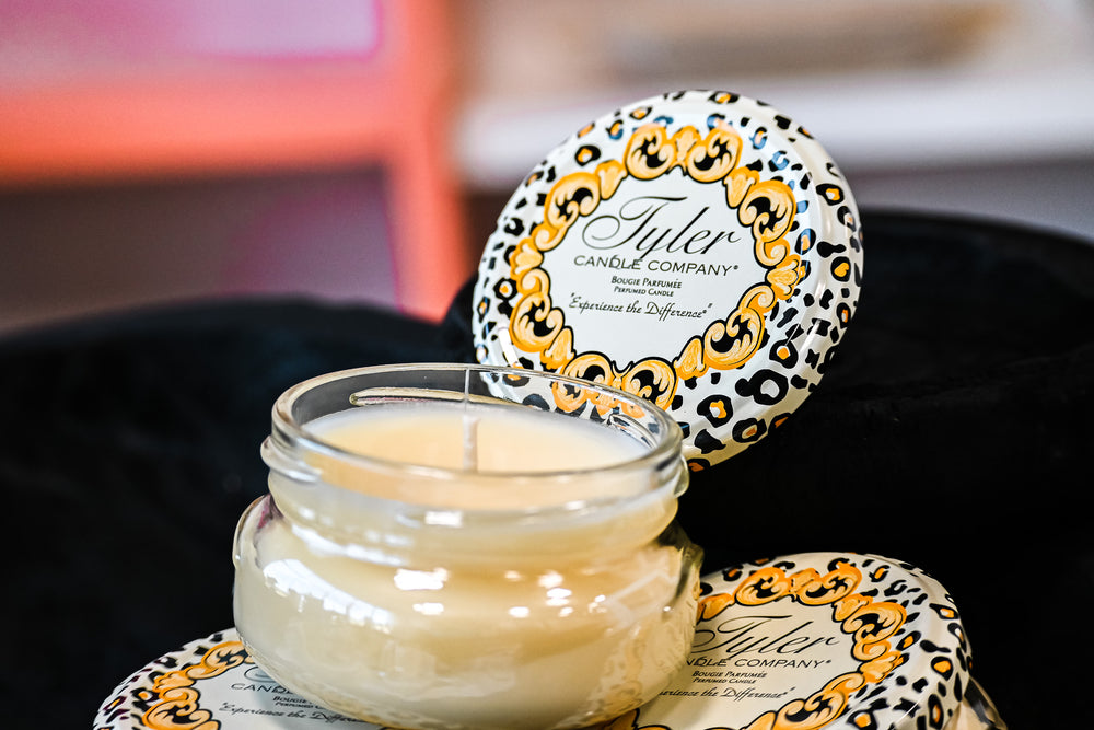 Tyler Candle Company pineapple scented candle in a clear glass jar with decorative lid on black fabric