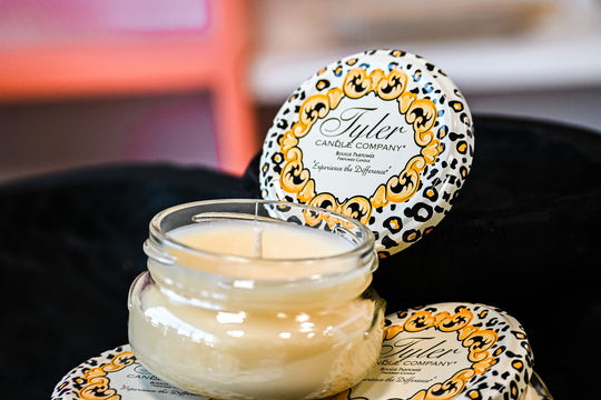 Tyler Candle Company pineapple scented candle in a clear glass jar with decorative lid on black fabric