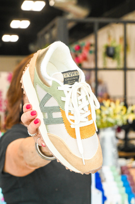 Light brown and green Vintage Havana sneakers held by person in store with floral background