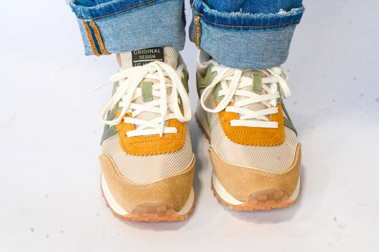 Vintage Havana sneakers in beige and mustard colors with white laces worn with rolled blue jeans