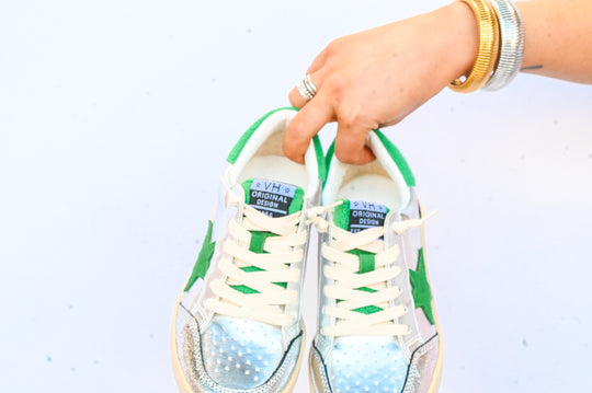 Hand holding a pair of Vintage Havana sneakers in white and green with metallic silver details