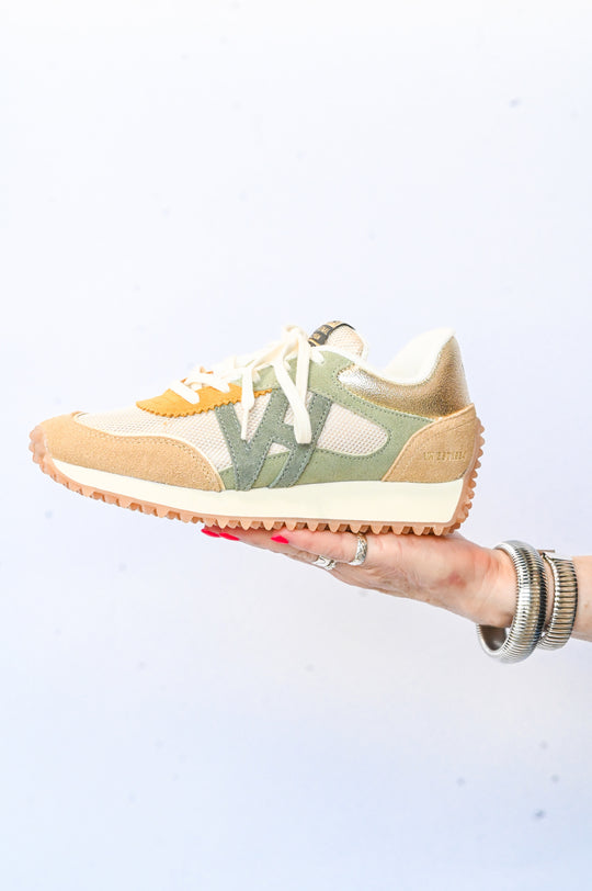 Light brown and green Vintage Havana sneakers with white laces held in a hand against a white background
