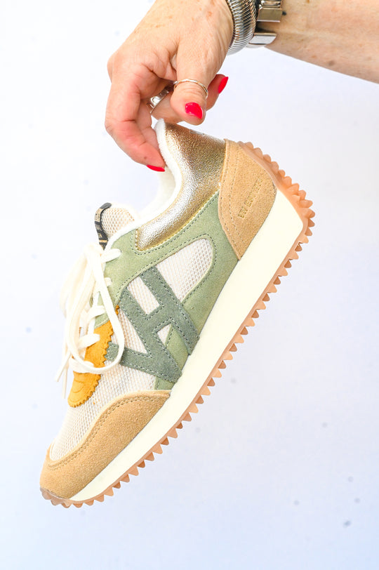 Hand holding a Vintage Havana sneakers in beige green and white with textured sole