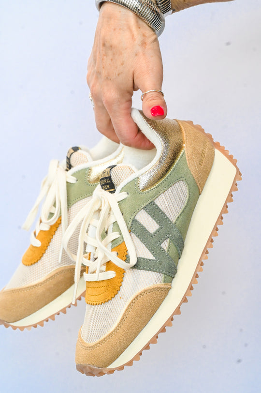 Hand holding beige and green Vintage Havana sneakers with white laces and rubber soles