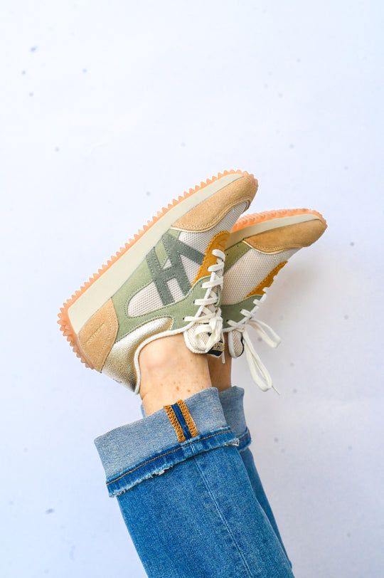 Green and tan Vintage Havana sneakers worn with blue cuffed jeans against white background