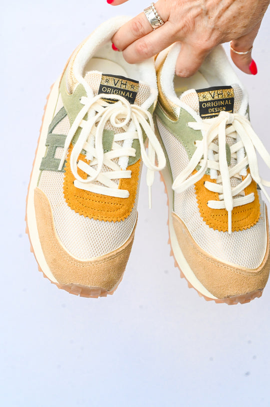 Vintage Havana sneakers in beige with white laces olive accents and mustard details held by hand