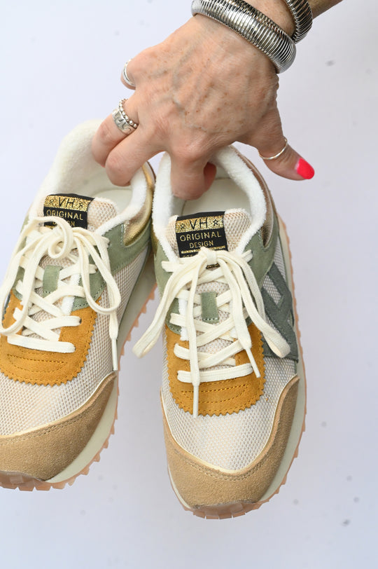 Hand holding a pair of Vintage Havana sneakers in beige, mustard, and green color with white laces