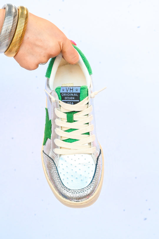 Hand holding a Vintage Havana sneakers with green star detail and white laces