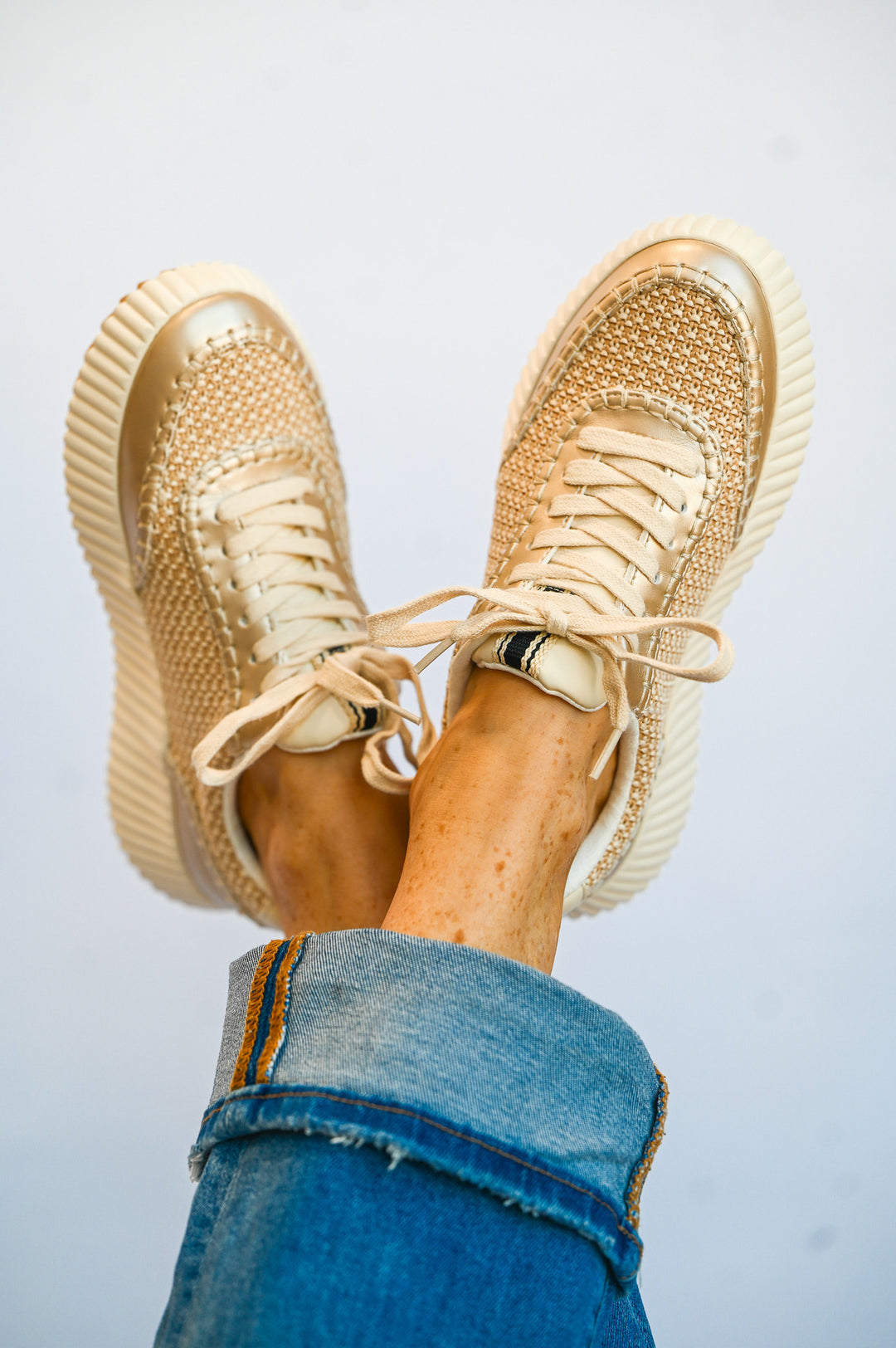 ShuShop gold sneaker fashion with woven design and thick sole worn with rolled-up jeans
