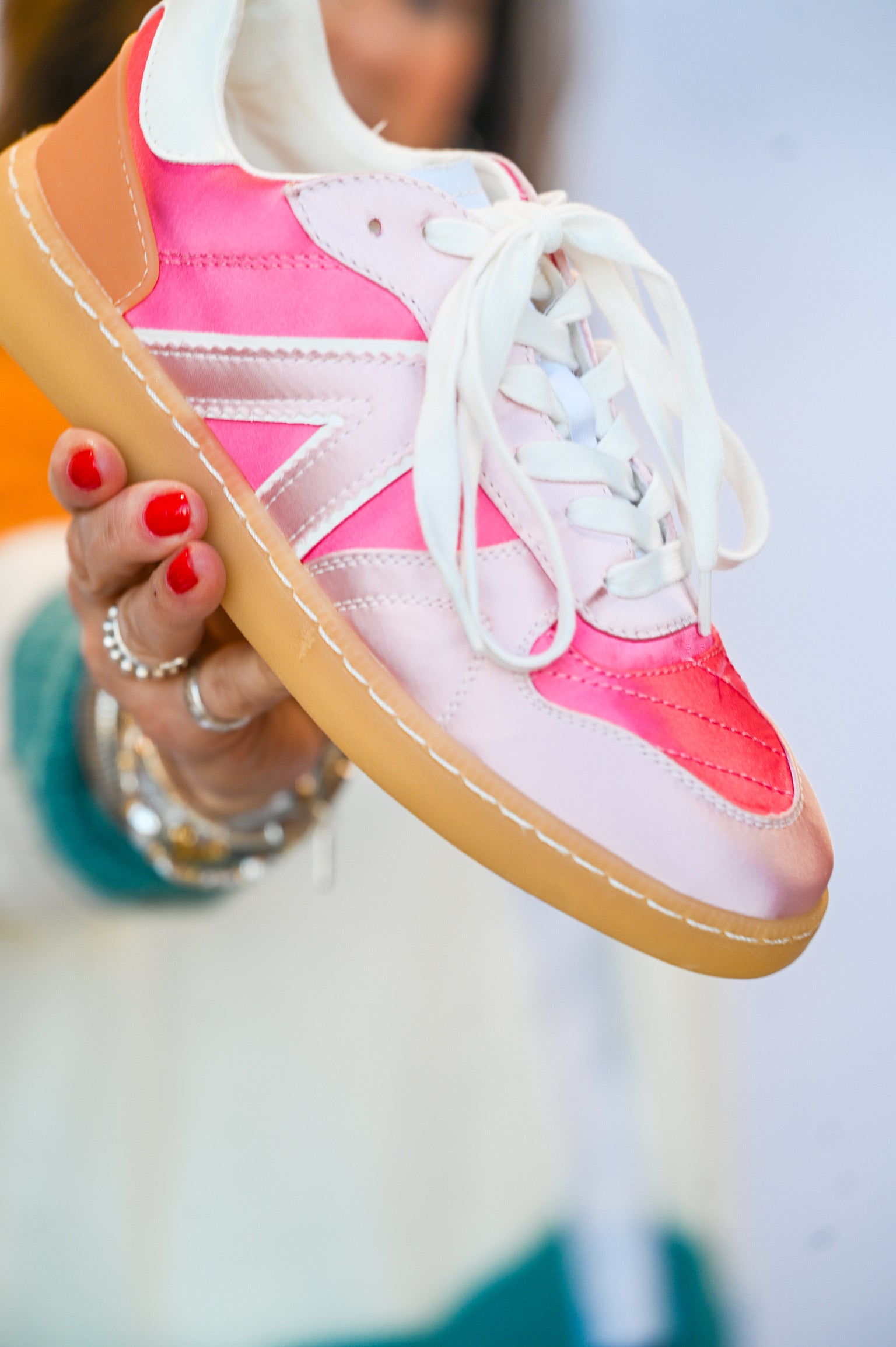 MIA Vesta light pink sneakers with white laces and tan sole held by person with red nail polish