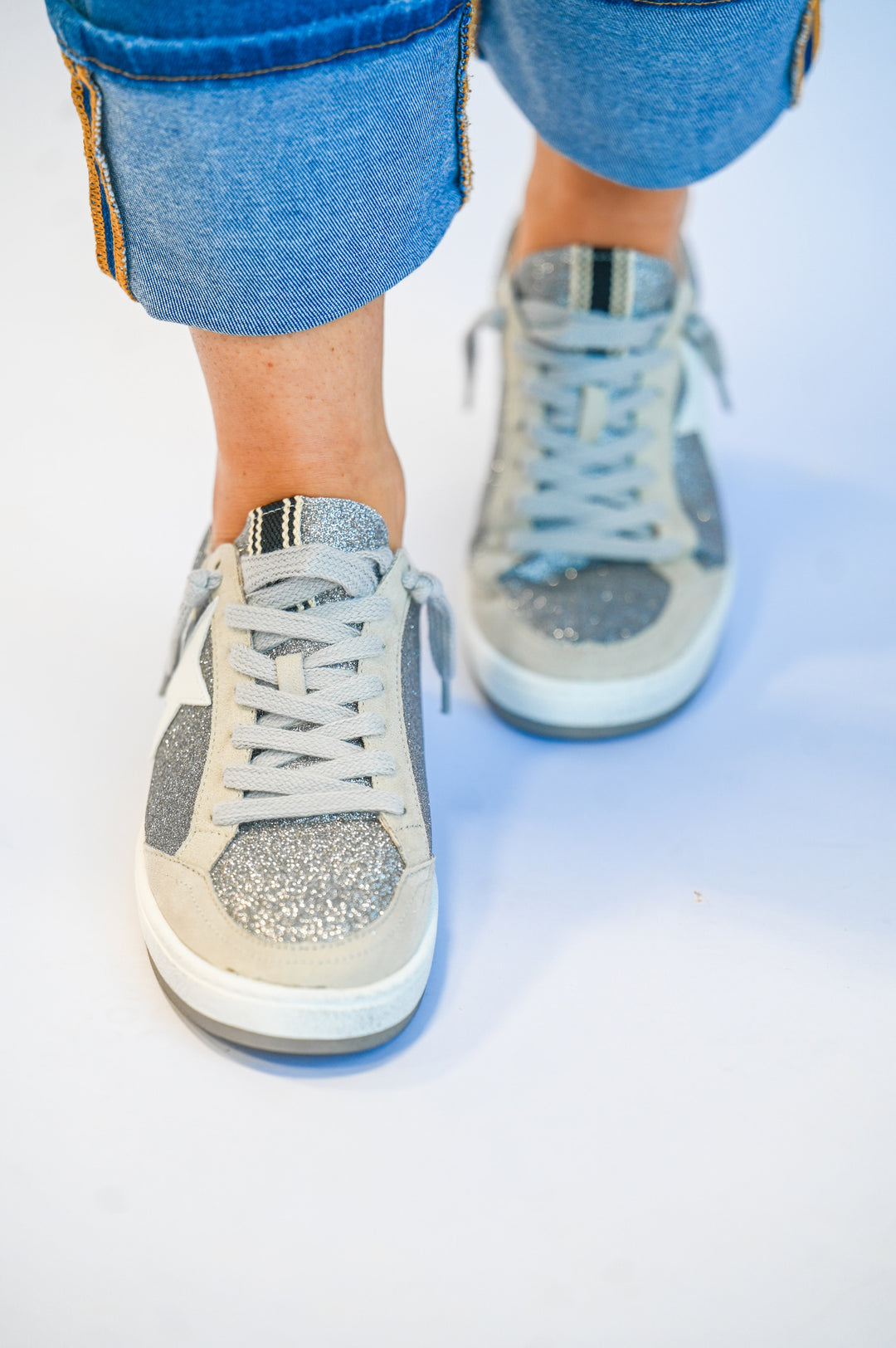 ShuShop Paz Glitter Sneaker in silver with glitter accents worn with rolled-up jeans