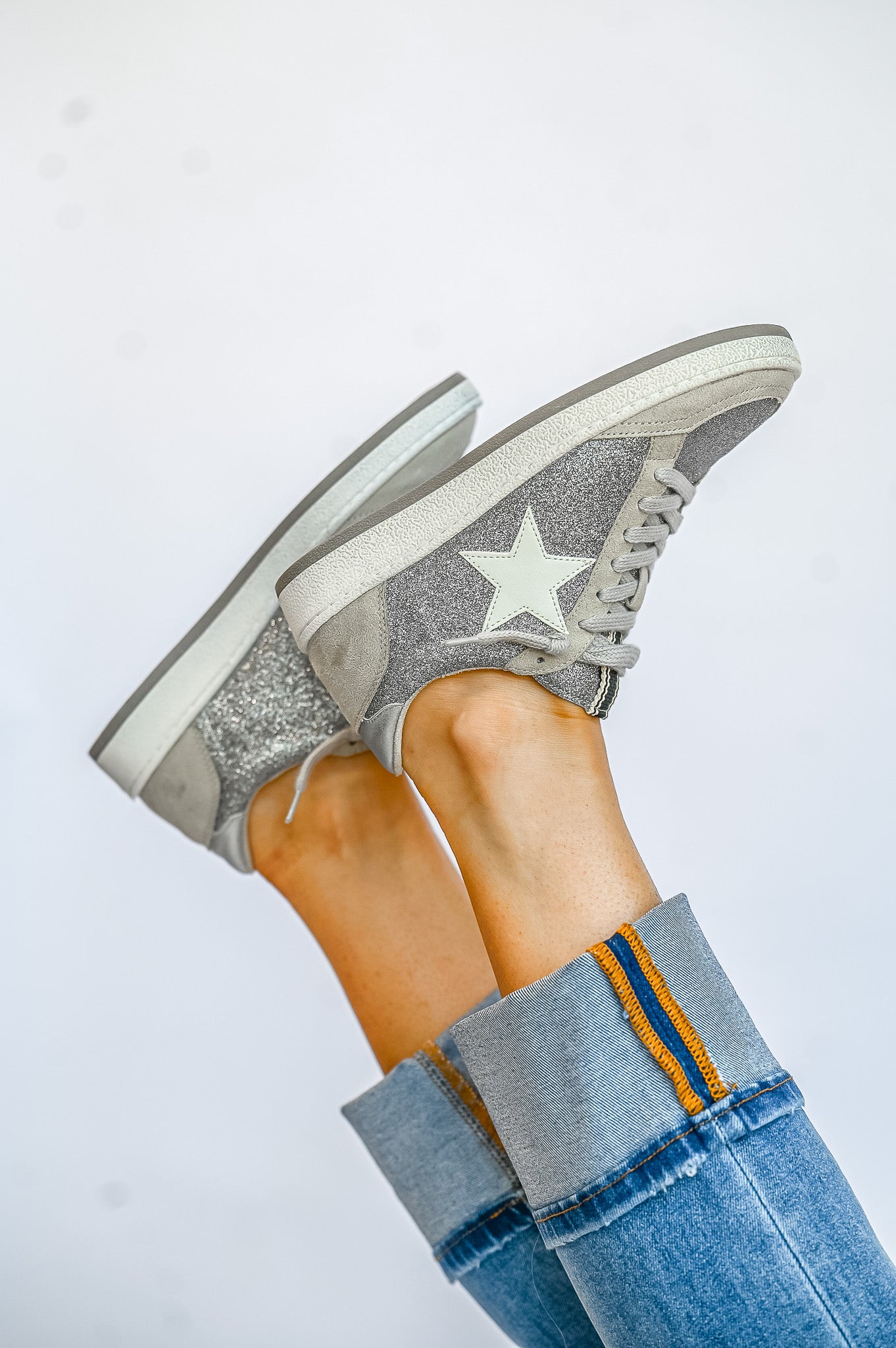 ShuShop Paz Glitter Sneaker in silver with star detail worn with cuffed blue jeans
